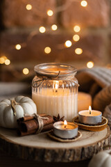 Autumn home composition with aromatic candle, dry citrus, cinnamon, anise. Aromatherapy on a grey fall morning, atmosphere of cosiness and relax. Wooden background close up copy space