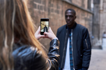 Fototapeta premium Girlfriend making photograph of her boyfriend in the street.
