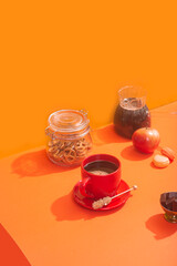 Black coffee in a red mug on an orange background. Goodies for coffee.
