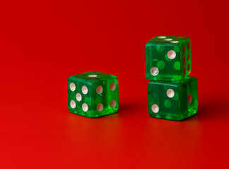 Three green translucent dice on a red background, two of them are stacked