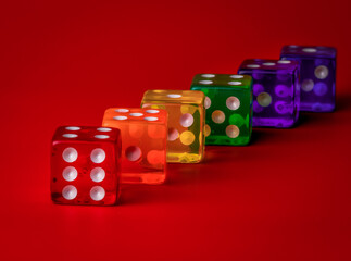 six translucent dice of different colors aligned on a red background