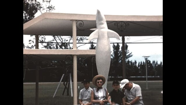 The Dolphin Statue 1957 - A family sits at the base of a dolphin statue while visiting a Miami park in 1957. 