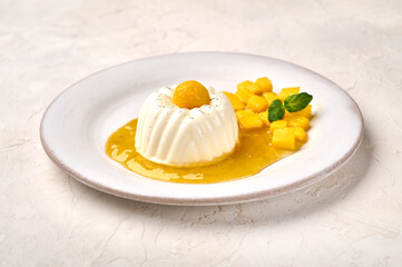 Homemade panna cotta with natural vanilla pod, mango syrup and mint, high key, close up