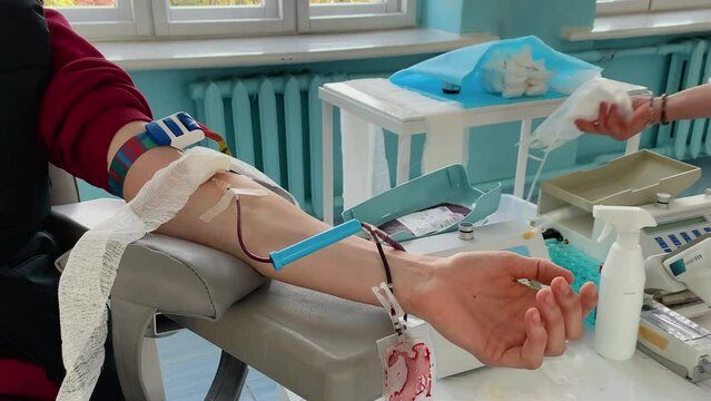 Blood donor at donation, transfusion. Close up right arm of a business man receiving blood in hospital. Healthcare and charity. World blood donor day - June 14