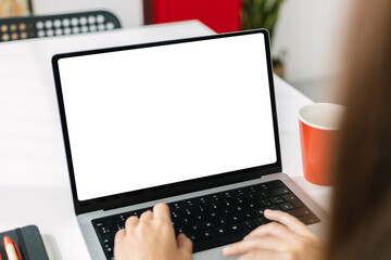 Mock up image of young business woman working on laptop computer with white blank screen on modern office