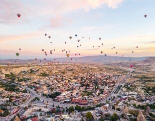 Hot-air ballon attraction organized in Turkish town named Cappadocia. Beautiful sunrise. Dozens of colourful balloons with tourists in gondolas over candy-coloured sky background. High quality photo