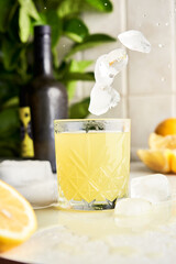 Ice falling on a traditional italian homemade lemon alcohol drink liqueur limoncello 