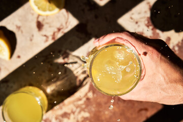 Unrecognizable man's hand holding a glass of fresh lemonade. Top view