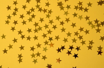 Golden stars on yellow background. Abstract background texture.