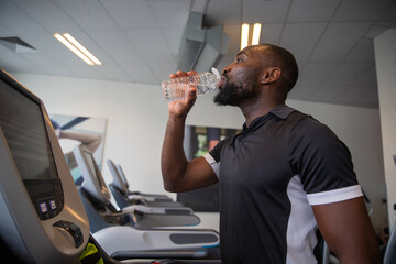 A boy drinks water while training in the gym, concept of hydration in sport