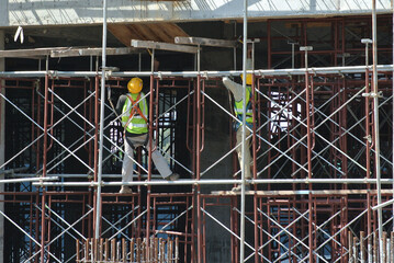 PERAK, MALAYSIA -APRIL 05, 2016: Construction workers wearing safety harness and installing scaffolding at high level in the construction site. 
