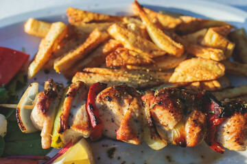 View of Souvlaki on a plate - traditional greek cuisine dish with grilled bbq chicken with french fries and tzatziki sauce served in a taverna cafe streets of Kerkyra, Corfu, Greece