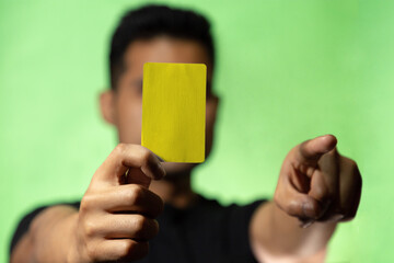 
Hombre mostrando tarjeta roja o amarilla en fondo verde concepto de árbitro futbol o deporte en general. Amonestación deportiva.
