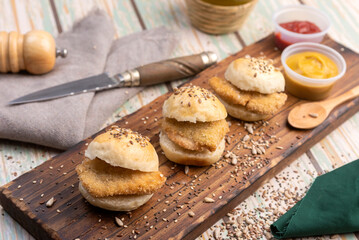 small milanesa sandwiches breaded meat for cold buffet with homemade seed bread on a wooden board and different sauces