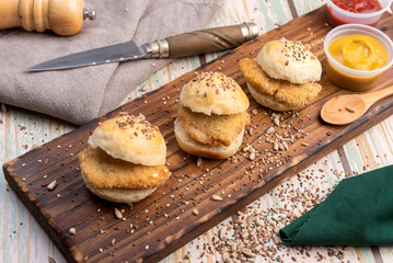small milanesa sandwiches breaded meat for cold buffet with homemade seed bread on a wooden board and different sauces