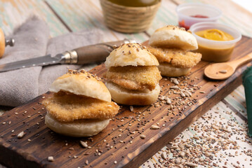 small milanesa sandwiches breaded meat for cold buffet with homemade seed bread on a wooden board and different sauces