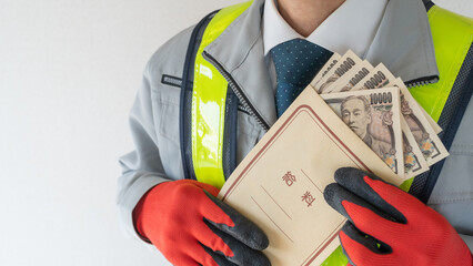 安全ベストの作業服男性と日本語の給料袋