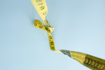 Tailors meter is hanging down, on a blue background. Measuring tape for sewing. Flatley. 