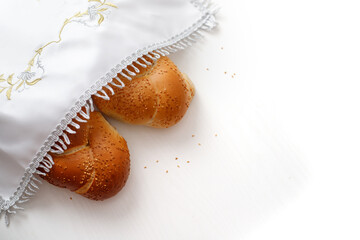 Challah bread covered with a special napkin on white background. Traditional Jewish Shabbat ritual. Shabbat Shalom.