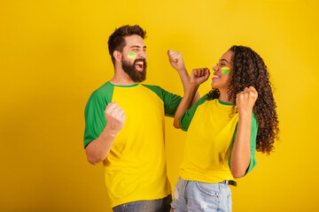 couple of brazil soccer supporters, dressed in the colors of the nation, black woman, caucasian...