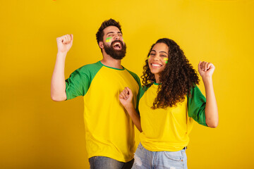 couple of brazil soccer supporters, dressed in the colors of the nation, black woman, caucasian...