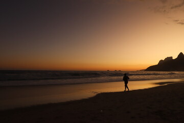 Rio de Janeiro, RJ, Brazil, 2022 - People walking in silhouette at Ipanema Beach at sunset