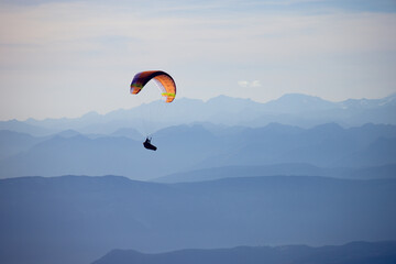 Paraglider flying along mountains.