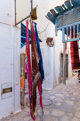 Colorful scarves sold in a street market Quiet street in Medina of Hammamet, Tunisia