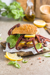 Big burger with octopus and lemon. Large sandwich stuffed with seafood. American fast food concept © Maria
