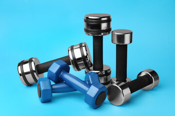 Many different stylish dumbbells on light blue background