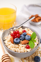 Oatmeal served with berries. almonds and mint on white table, above view