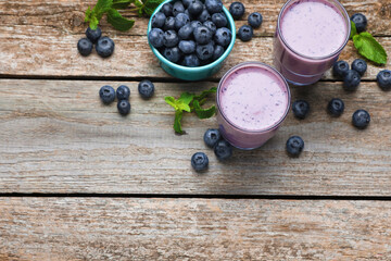 Freshly made blueberry smoothie on wooden table, flat lay. Space for text
