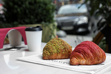 Delicious croissants and paper cup of coffee on white table