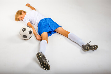Young male soccer player lying unconscious injured on the ground