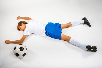 Young male soccer player lying knocked out injured on the ground