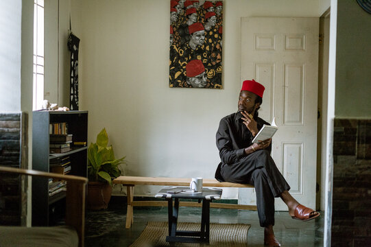 an igbo man in his native attire reading a book