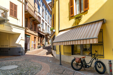 A bicycle is parked on a colorful street of shops and cafes in the historic center of the lakefront town of Menaggio, Italy, on the shores of Lake Como.
