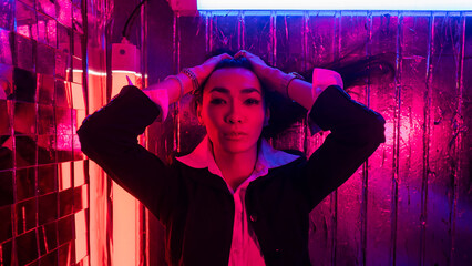 Portrait of Asian man with long hair in neon studio.