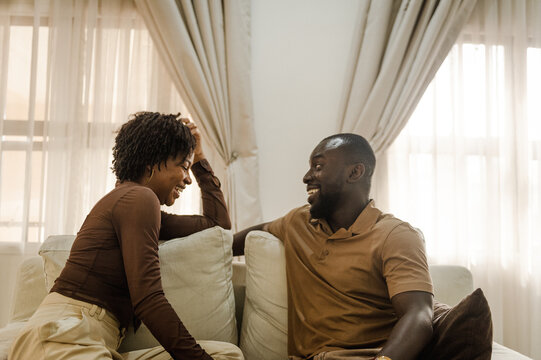 black couple sitting on sofa and laughing together