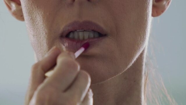 Close up, middle aged brunette woman applying lipstick in slow motion