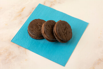 Three chocolate fudge sandwich cookies on blue snack napkin on table