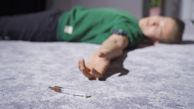 Drug addicted man is unconscious from overdose.
The man who takes a high dose of medicine from the syringe is unconscious.
