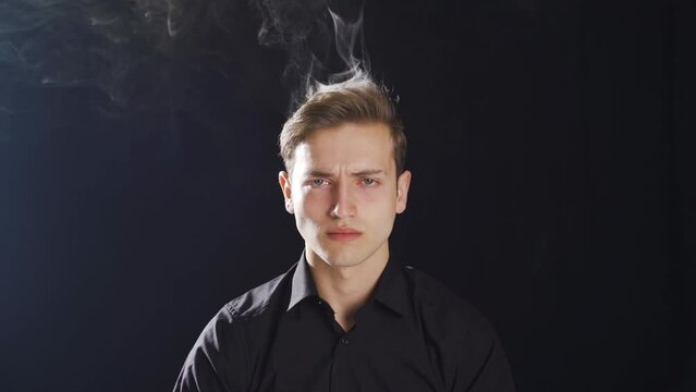 Frustrated young man is angry and smoke is coming out of his head.
Smoke is rising from the head of the angry young man.
