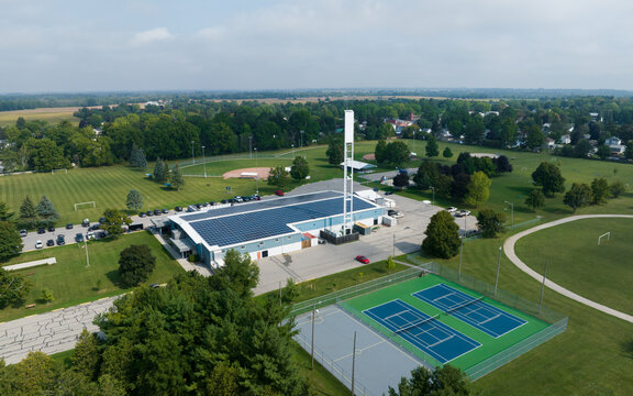 An aerial view looking at a rural sports building and facility with solar panels installed across the roof.
