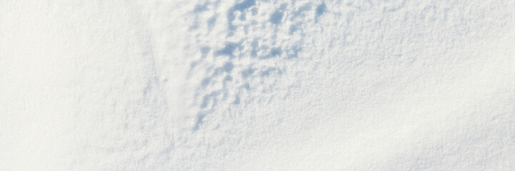 Obraz premium Beautiful winter background with snowy ground. Natural snow texture. Wind sculpted patterns on snow surface. Wide panoramic texture for background and design.
