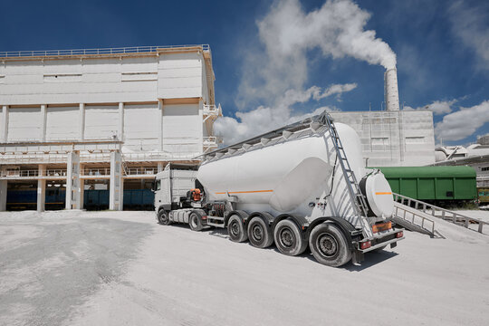 Modern cement trailer near warehouse of production plant