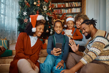 Happy black multigeneration family talking to someone via video call on Christmas day,