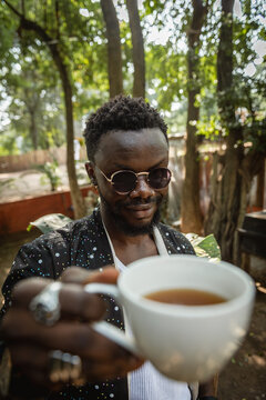 A man holding up a cup of tea