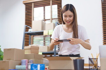 Online business concept, Asian business women take a picture while packing product into parcel box