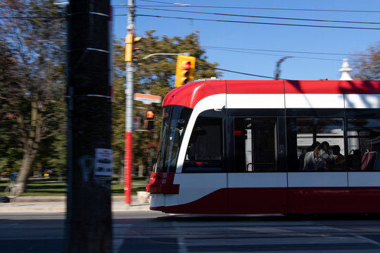 A modern streetcar, light rail, is seen on a downtown city street, urban area during a clear, blue sky day.
